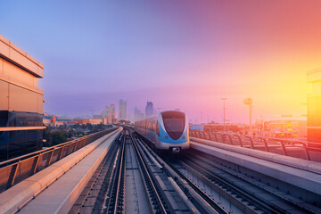 Wall Mural - Dubai cityscape, modern metro railway with skyscrapers, sunset. Traffic train and building with urban skyline background of city UAE