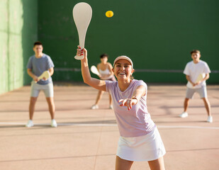 Wall Mural - Portrait of sporty young girl playing paleta fronton on outdoor court, ready to hit ball. Healthy and active lifestyle concept