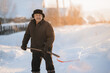 © Parilov - Elderly man cleaning snow with shovel after snowstorm, sunlight