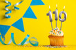 Lighted birthday candle number 110 - Yellow background with blue pennants