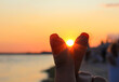 Silhouette of fingers sign, mini heart on sunset sky at the seaside. Korean body language symbol of love with your fingers. Valentine's Day concept.