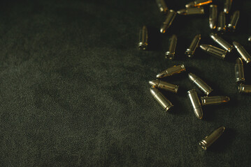 bullets for a combat pistol 9 mm gold color lies on a dark green or khaki background top view close-up