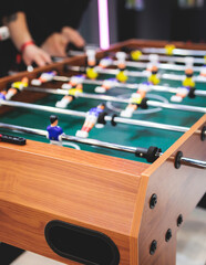 Group of friends playing kicker in a sports bar room, colleagues teammates play table football, table soccer game in the office, having fun, tabletop football match competition at work