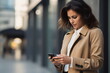 © duyina1990 - Young woman in a trench coat using her phone in the city