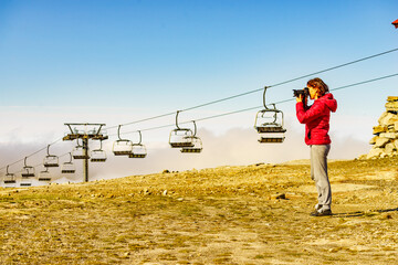 Sticker - Woman with camera in mountains take travel photo