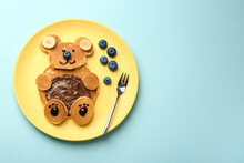 Creative Serving For Kids. Plate With Cute Bear Made Of Pancakes, Blueberries, Bananas And Chocolate Paste On Light Blue Table, Top View. Space For Text