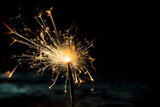Fototapeta Sypialnia - sparkler creating bright light on a dark background