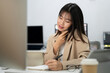 © bongkarn - A young, beautiful Asian businesswoman is busy with her work in the office, talking on the phone.