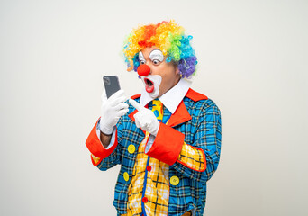 Wall Mural - Mr Clown. Portrait of Funny face Clown man in colorful uniform standing holding smartphone. Happy expression male bozo in various pose with cellphone on isolated background.