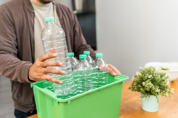 A young man arranged plastic bottles into a box. He assumes plastic bottles will sort of trash before throwing them into the bin. World environment day. Recycle waste reduce environmentally friendly