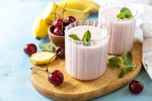 Fresh Seasonal Smoothies. Smoothies With Sweet Cherry And Banana With Yogurt On Wooden Board On A Stone Background. Copy Space.