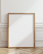 © Michael - mockup of a blank large light oak frame leaning against a white wall.