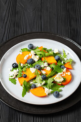 Wall Mural - arugula persimmon cheese berries salad, top view