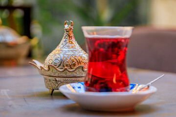 Sticker - Traditional tulip shaped glass of Turkish mulberry tea or chai, lokum Turkish delight candy served in a silver bowl at a restaurant, Istanbul, Turkey