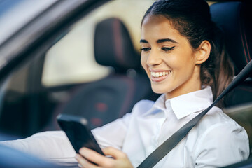 portrait of a happy woman driving a car and smiling at the phone.