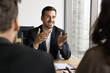 © fizkes - Positive successful business professional man meeting with investors, sitting at table, talking to project partners, explaining management strategy, discussing cooperation, speaking, smiling