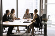 © fizkes - Happy young African American business leader woman holding brainstorming meeting with employees. Multiethnic team talking at office space conference table, laughing