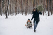 © Ananass - a happy father is sledding his children in the middle of a pine forest with a Christmas tree that they chose together and cut down for Christmas