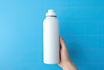 Wall Mural - hand holding a stainless drink bottle on a blue background