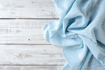 Poster - Folded light blue tablecloth with polka dots placed on a bleached wooden table in a top view image Ample space for your text