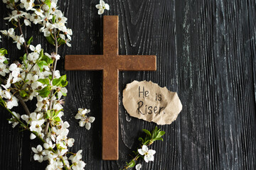 Wall Mural - Cross with flowers on a wooden background with the inscription Christ is Risen. Easter concept. Cross symbolizing the death and resurrection of Jesus Christ