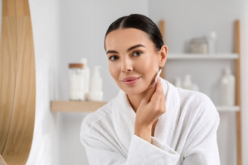 Wall Mural - Beautiful woman removing makeup with cotton pad indoors