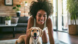 A smiling African American woman exercising on a mat and a puppy dog disturbing her. Modern apartment background. 