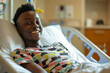A young black patient lying in a hospital bed smiling