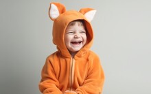 Child In A Fox Costume With A Tail, Smiling, On A Light Background, Space For Text 