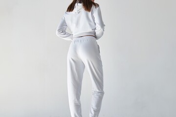 Wall Mural - Back view of a young woman wearing white minimalist sweatpants. Step into Comfort with a Chic White Outfit Perfect for Casual Elegance. Sportwear mock-up. Girl in white pants.