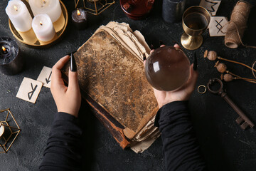 Wall Mural - Witch with spell book and crystal ball on dark background