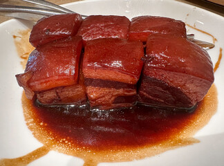 traditional classic Chinese style red braised Pork belly stewed with Chinese spices and rice wine, also know as Hong Shao Rou. Served on white plate and cut into small 6 pieces.