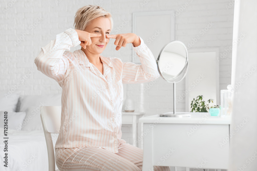 Mature woman doing face building exercise in bedroom