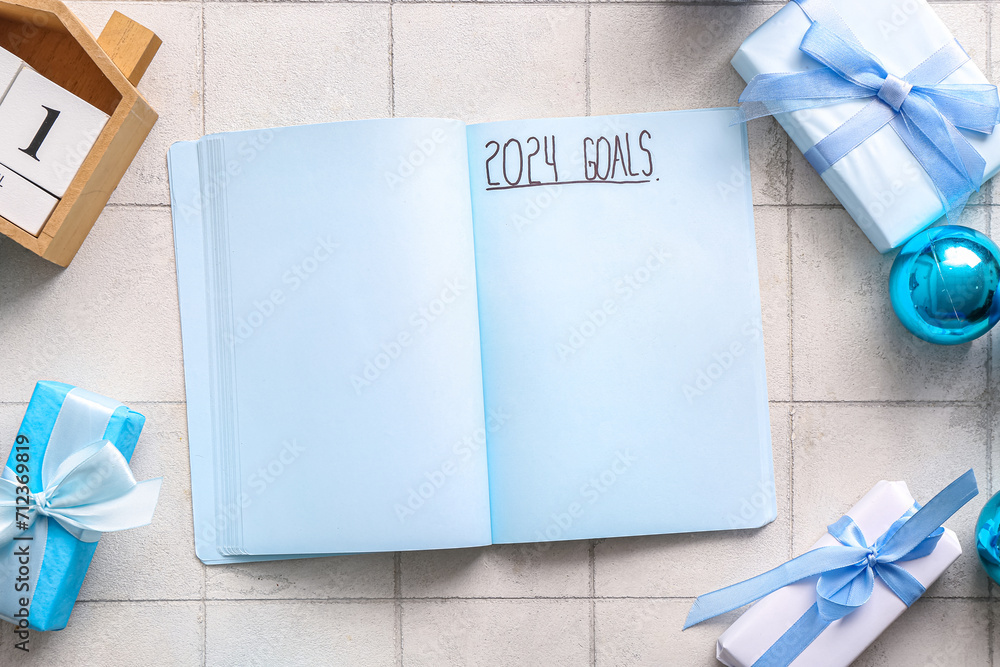Notebook with text 2024 GOALS and Christmas decor on white tile background