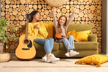 Wall Mural - Young woman giving music lessons to teenage  girl with acoustic guitar at home