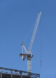 Hoisting tower crane on the top section being constructed of modern high skyscraper  building against blue cloudless sky