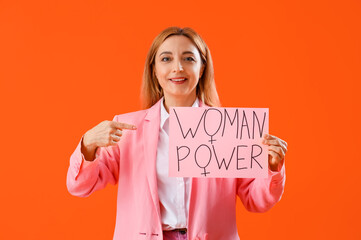 Wall Mural - Mature business lady pointing at paper with text WOMAN POWER on red background