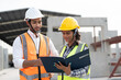 © Supachai - Asian male and female civil engineers wearing vest and helmet safety discussing on document at factory making precast concrete wall in construction site.