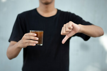 Front view close up of man hand holding coffee cup with thumbs down at home