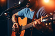 © Ahmed - Male musician playing acoustic guitar behind microphone, close-up, recording in a music studio