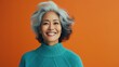 © inna717 - Portrait of an attractive cheerful gray-haired woman having fun, isolated on a bright turquoise background with a camera