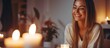 Content woman finds joy in candle scent, smiling at lit candle in cozy home atmosphere at night. Self-care and relaxation.