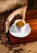 Cup of latte coffee and coffee beans on old wooden background