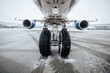 Front view of airplane landing gear. Winter frosty day at airport during snowfall. .