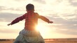 © SUPER FOX - Son sits on father shoulders stretching arms wide. Dad with boy takes walk across field surrounded by natural scenery. Father and son relish serene beauty of countryside with panoramic views at sunset