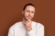 © deagreez - Photo of uncertain serious guy dressed white pullover arm chin thinking isolated brown color background