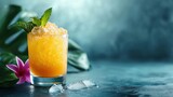  a glass of orange juice with a mint garnish on the rim and ice cubes on the rim.