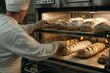 © Наталья Добровольска - an oven worker preparing several loaves of bread