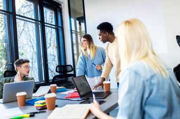 Diverse group of young business people working on new project together in office.