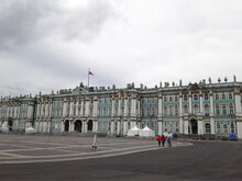 Hermitage Museum. People Go To The Museum. Flag Of Russia On The Building. Cloudy Day In St. Petersburg.